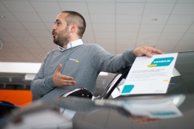 Personne présentant les services après-vente d'une voiture d'occasion.