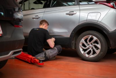 Professionnel réparant la carrosserie d'une voiture d'occasion en concession.