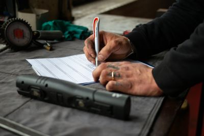 Personne signant un contrat d'engagement de reprise pour sa voiture d'occasion.