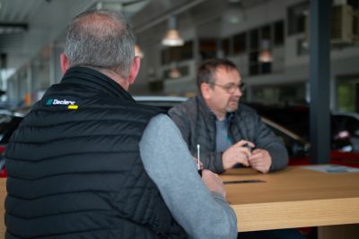 Employé click2move by Declerc proposant un contrat d'engagement de reprise pour une voiture d'occasion.